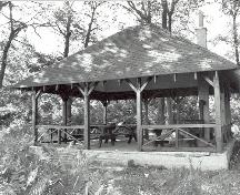 General view of the Sheltar, showing the hipped roof, exposed rafter ends, wood support posts and diagonal brackets, 1992.; Parks Canada Agency / Agence Parcs Canada, 1992.