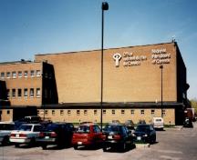 La façade principale de l'Office national du film, qui montre le revêtement extérieur en brique de couleur chamois, 1998.; Public Works and Government Services Canada / Travaux publics et Services gouvernementaux Canada, 1998.