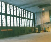 Vue de l'intérieur de l'aérogare de Churchill, qui montre les fondations et le plancher en béton, et la charpente de bois avec poutres d’acier autour des portes du hangar.; Transport Canada / Transports Canada