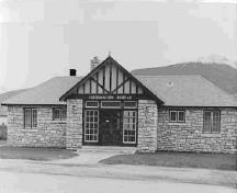 Vue de la façade générale de l'édifice Rescue, qui montre l’agencement symétrique des portes et des petites fenêtres à carreaux multiples, 1950.; Parks Canada Agency / Agence Parcs Canada, 1950.