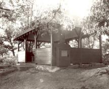View of the exterior of the Adelaide Island Picnic Shelter, showing the open design and unpartitioned interior space, 1992.; Parks Canada Agency / Agence Parcs Canada / Historica Resources Ltd., 1992.