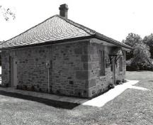 Corner view of the Defensible Lockmaster's House, showing the hipped roof and the original roof framing and the chimney, 1989.; Parks Canada Agency / Agence Parcs Canada, Couture, 1989.