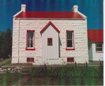Front view of the Old Dwelling, Cove Island, demonstrating the whitewashed exterior walls of rough faced, rusticated stone set in even courses, with a slightly projecting basement course, 1990.; Canadian Coast Guard/Garde côtière canadienne, 1990.