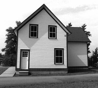 Façade of the Store House, showing its clapboard-clad, gable-roofed domestic exterior form, 1989.; Parks Canada Agency / Agence Parcs Canada, Couture, 1989.