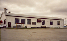 General view of Hangar 13, showing its varying fenestration and one-storey rectangular massing with a low bowed roof, 1992.; Department of National Defence / ministère de la Défense nationale, 1992.